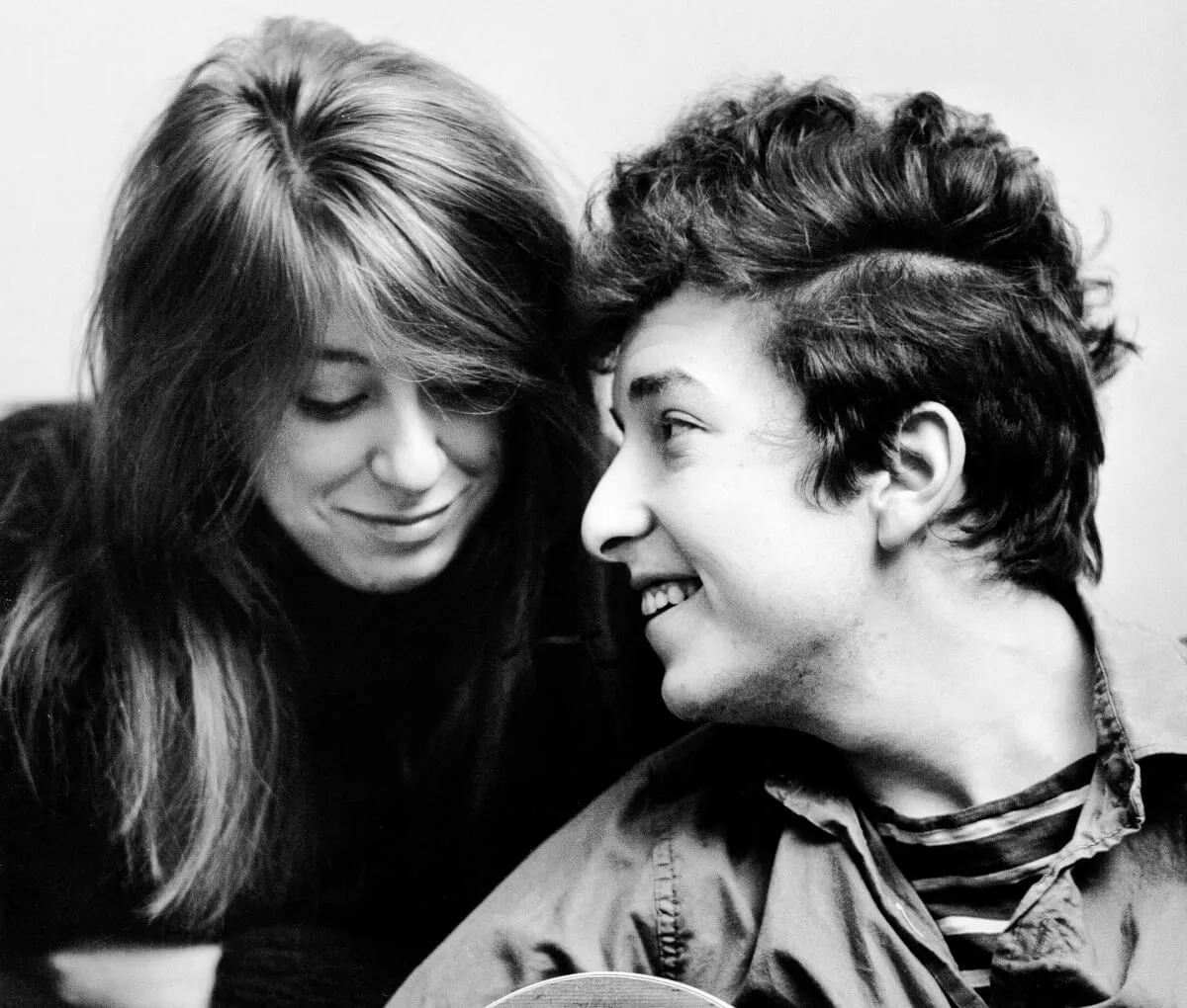 A black and white picture of Suze Rotolo and Bob Dylan looking at each other.