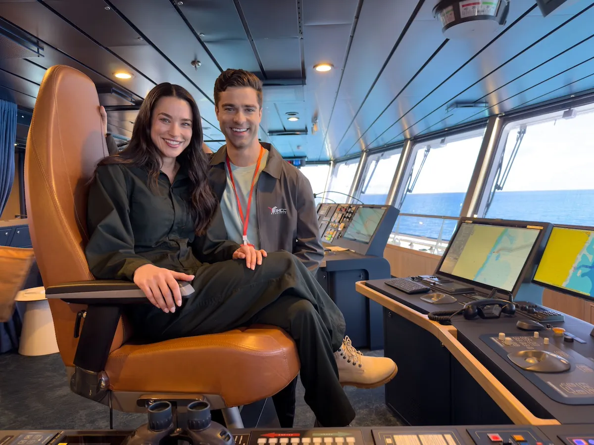 Smiling man and woman on the bridge of a ship in the Hallmark movie 'Polar Opposites'